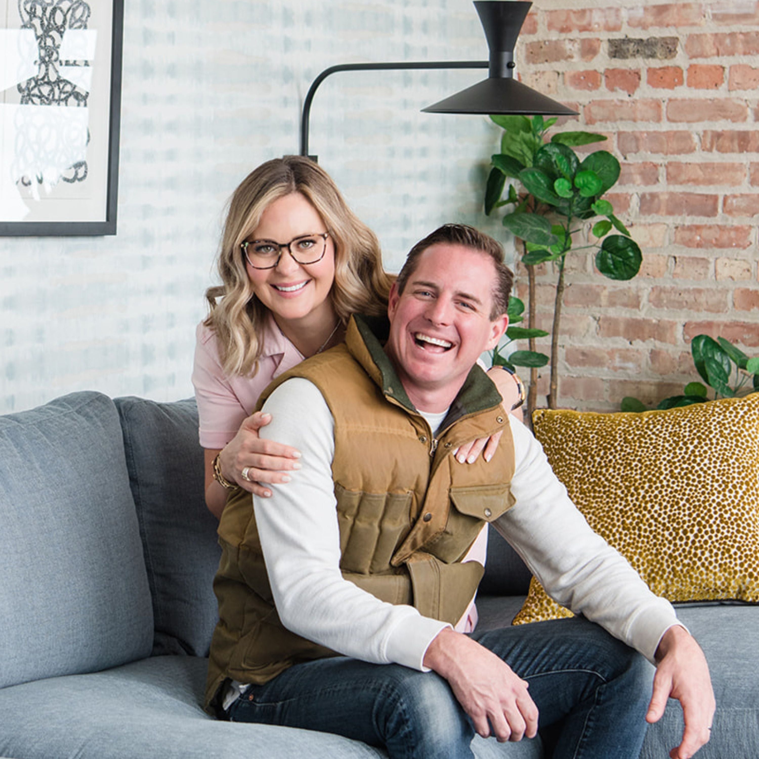 Meg and Joe Piercy sitting on a couch smiling 